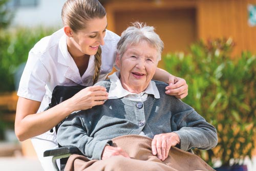 Pflegerin macht Spaziergang mit Seniorin im Rollstuhl